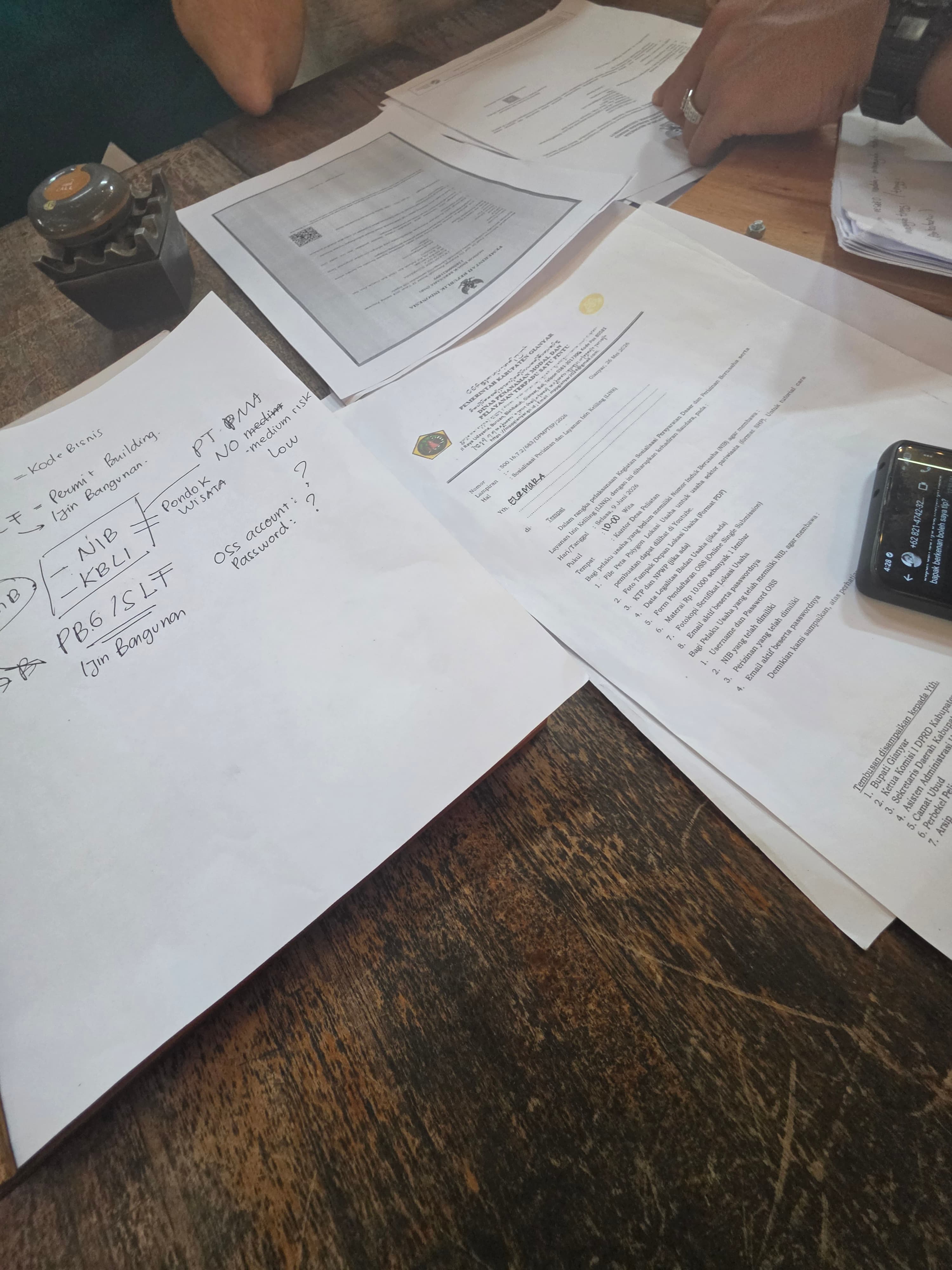 Documents officiels, notes manuscrites et un téléphone portable sur une table en bois sombre.